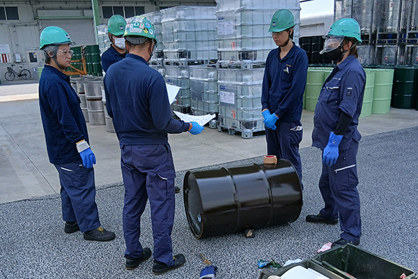 外で5人が輪になり話を聞いている様子