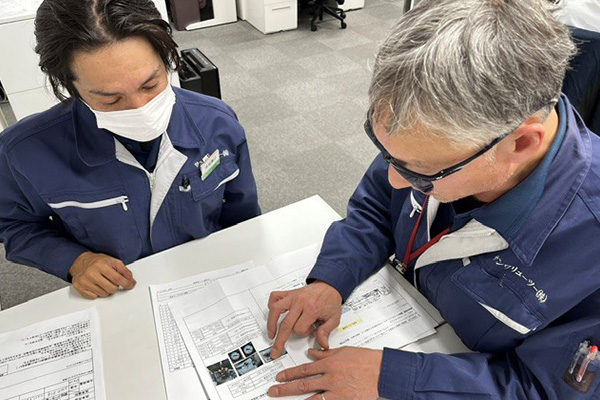机上で先輩が新人に資料の内容を教えている様子